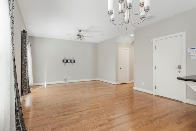 unfurnished living room featuring light wood-style flooring, baseboards, and ceiling fan with notable chandelier