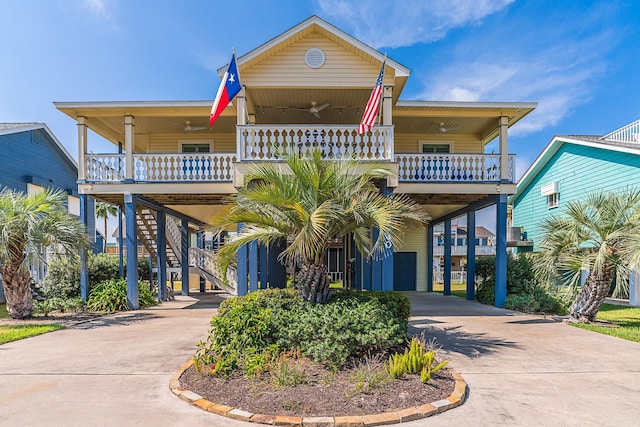 raised beach house with a carport, stairway, driveway, and a ceiling fan