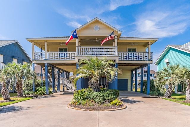 raised beach house with a carport, concrete driveway, a porch, and stairway