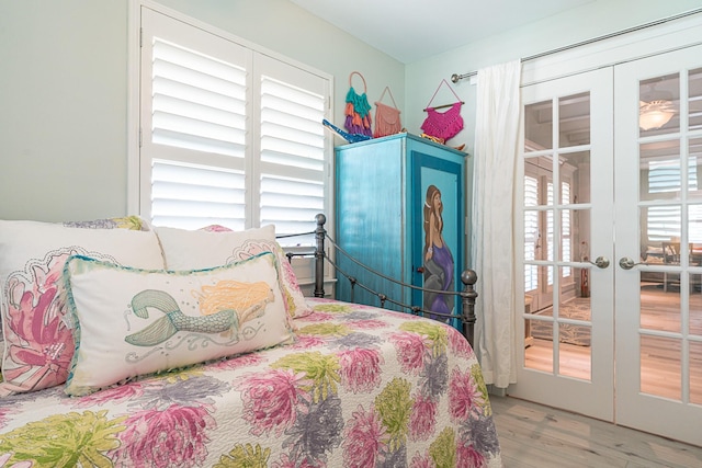 bedroom with multiple windows, wood finished floors, and french doors