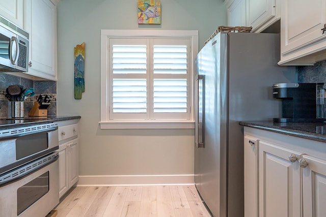 kitchen with stainless steel appliances, light wood-type flooring, backsplash, and baseboards