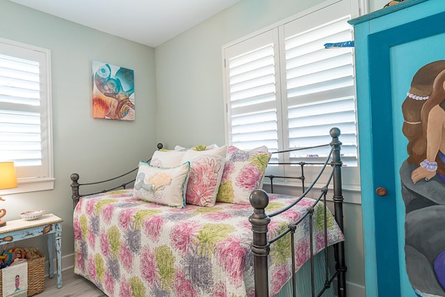 bedroom with multiple windows and wood finished floors