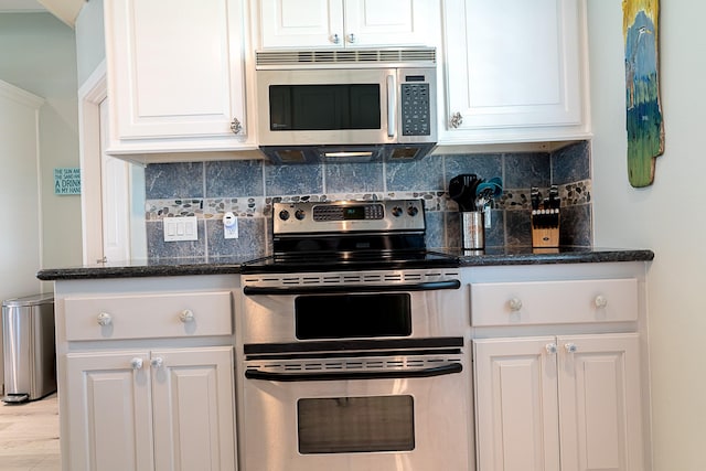 kitchen with dark stone counters, stainless steel appliances, tasteful backsplash, and white cabinets