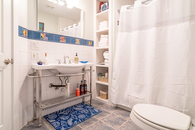 full bathroom featuring toilet, a sink, tile walls, decorative backsplash, and a shower with curtain