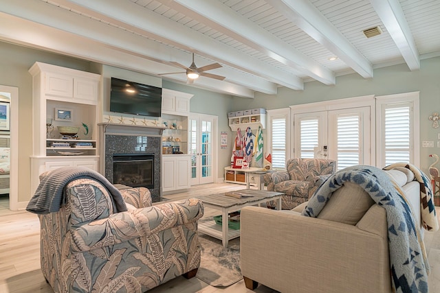 living room with light wood-style flooring, a fireplace, baseboards, and beam ceiling