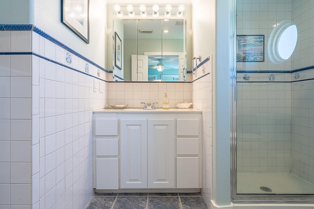 bathroom with tile walls, visible vents, a shower stall, vanity, and tile patterned floors