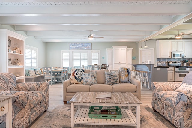 living room with beam ceiling, light wood-type flooring, and a ceiling fan