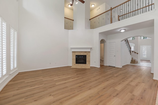 unfurnished living room featuring baseboards, a healthy amount of sunlight, a tile fireplace, and light wood-style floors