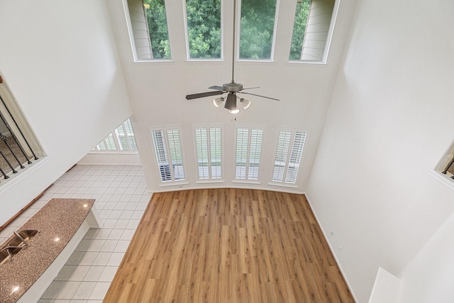 unfurnished living room with a high ceiling, a ceiling fan, and tile patterned floors