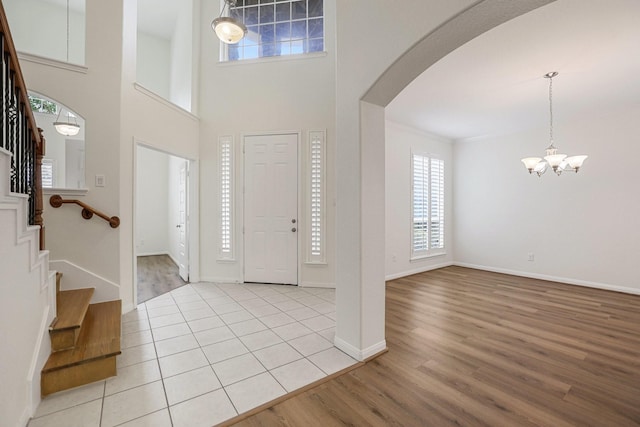 entryway with arched walkways, light wood finished floors, stairs, and baseboards