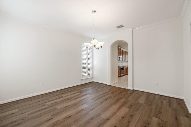 unfurnished dining area featuring arched walkways, visible vents, baseboards, light wood finished floors, and crown molding