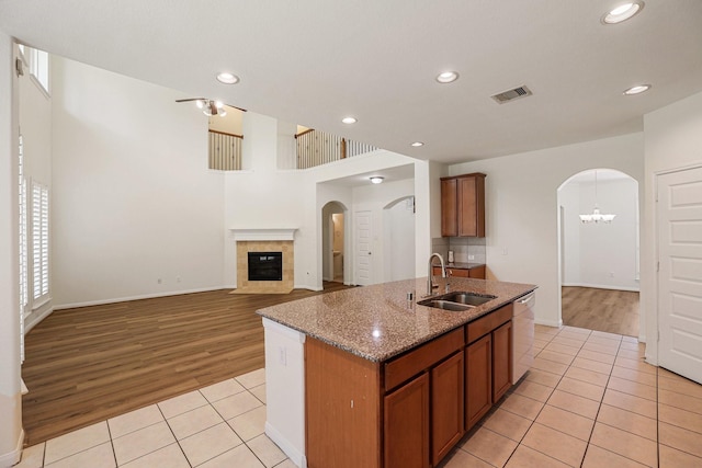 kitchen featuring light tile patterned floors, visible vents, arched walkways, white dishwasher, and a sink