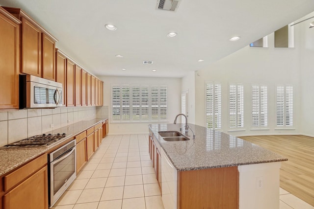 kitchen with tasteful backsplash, a center island with sink, visible vents, appliances with stainless steel finishes, and a sink