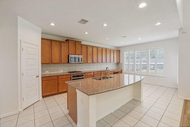 kitchen featuring a sink, visible vents, appliances with stainless steel finishes, brown cabinets, and tasteful backsplash