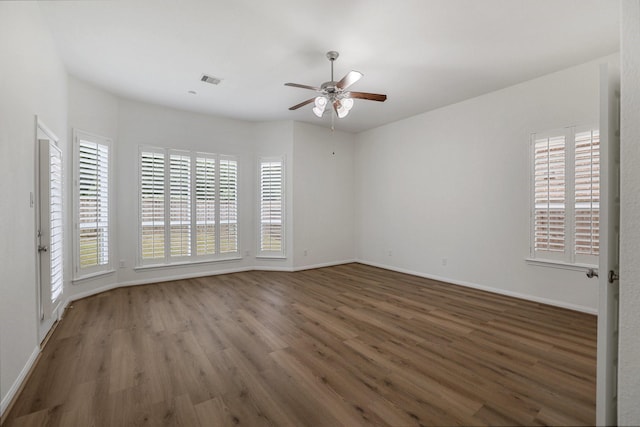 empty room with a ceiling fan, a wealth of natural light, baseboards, and wood finished floors