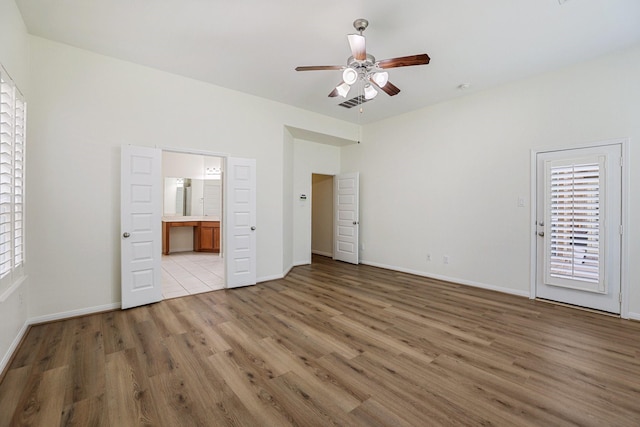 unfurnished bedroom featuring light wood-type flooring, ceiling fan, baseboards, and ensuite bathroom