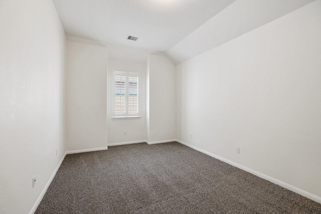 unfurnished room featuring lofted ceiling, baseboards, visible vents, and dark carpet