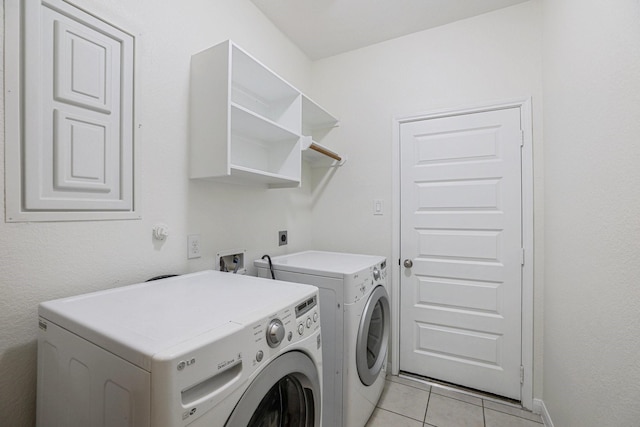 clothes washing area featuring washing machine and dryer, laundry area, and light tile patterned flooring