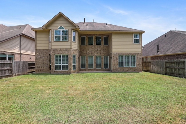 back of property with brick siding, a lawn, and a fenced backyard