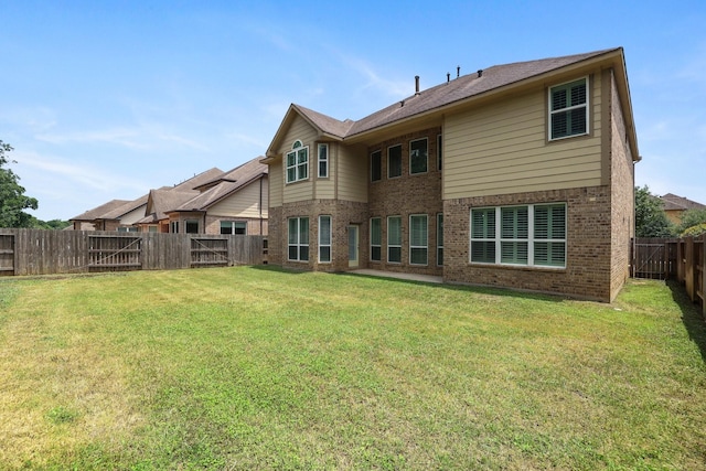 rear view of property featuring brick siding, a lawn, and a fenced backyard