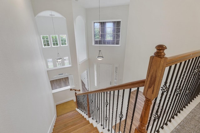 stairs with baseboards, a high ceiling, and wood finished floors