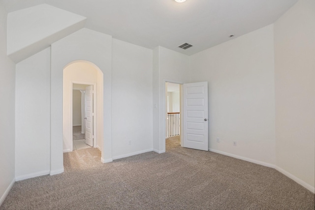 carpeted spare room featuring visible vents, vaulted ceiling, and baseboards