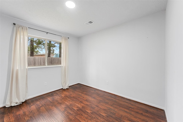 unfurnished room featuring baseboards, a textured ceiling, visible vents, and wood finished floors