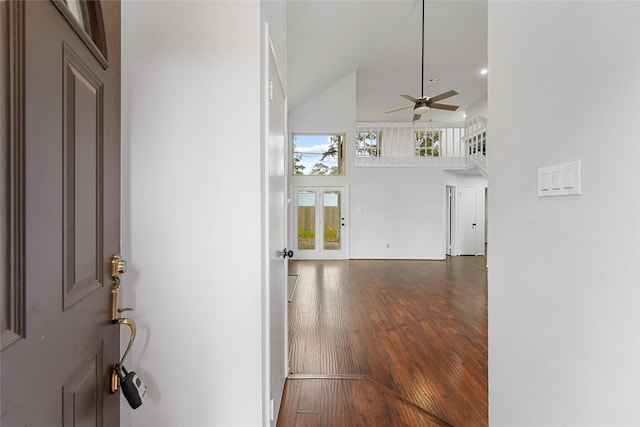 hall with a towering ceiling and wood finished floors