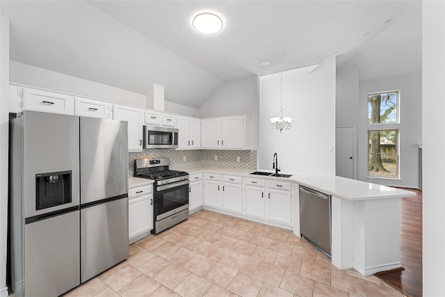 kitchen with stainless steel appliances, light countertops, a sink, and a peninsula