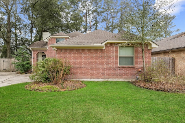 view of front of property with brick siding, a front yard, and fence