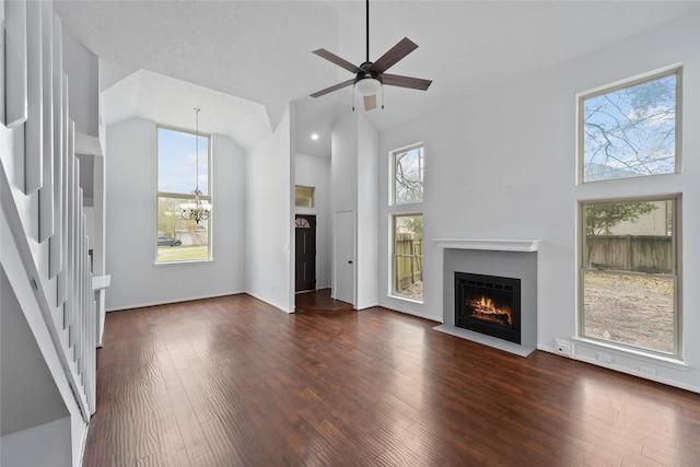 unfurnished living room with a fireplace with flush hearth, wood-type flooring, high vaulted ceiling, and ceiling fan with notable chandelier