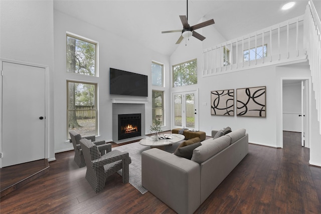 living area featuring a fireplace with flush hearth, wood-type flooring, high vaulted ceiling, and baseboards