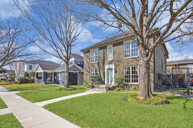 view of front of home with brick siding, a front yard, fence, and a residential view