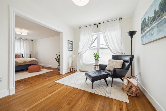 sitting room with baseboards and wood finished floors