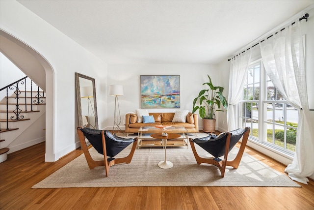 interior space featuring arched walkways, stairway, baseboards, and wood finished floors