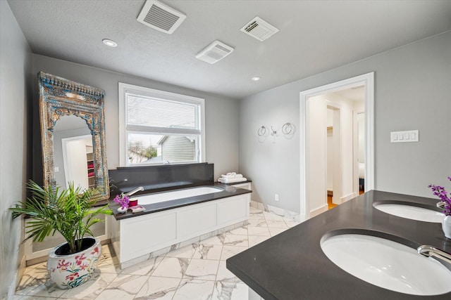 bathroom with a bath, marble finish floor, visible vents, and baseboards