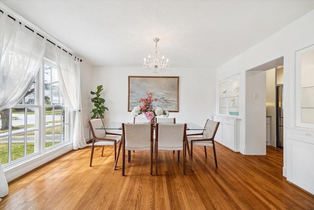 dining area featuring a healthy amount of sunlight, an inviting chandelier, and light wood-style floors