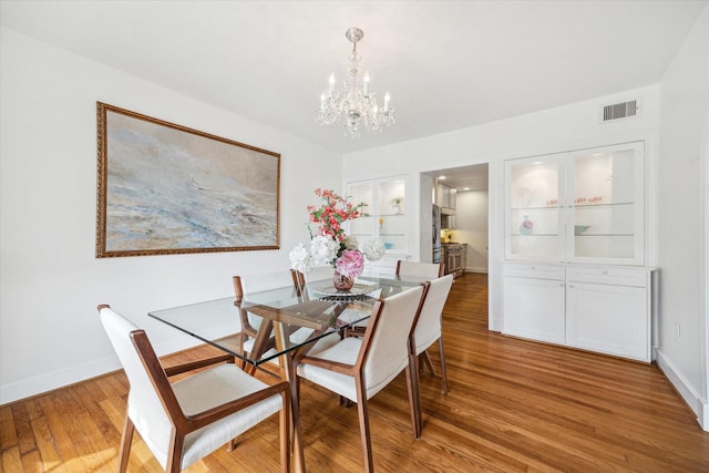 dining space with baseboards, a notable chandelier, visible vents, and light wood-style floors