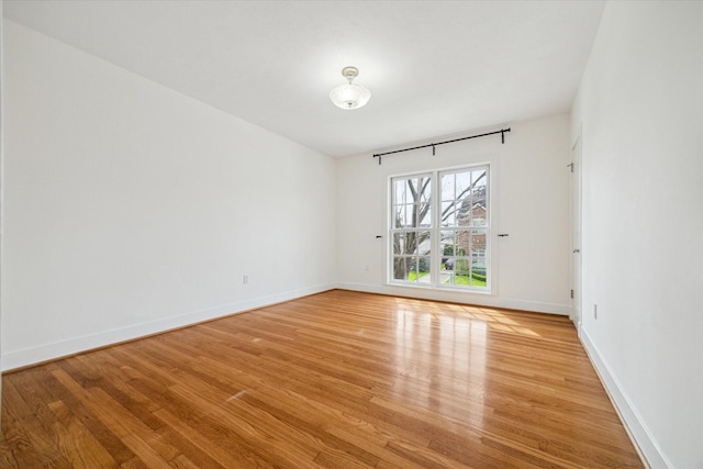 spare room featuring light wood-type flooring and baseboards