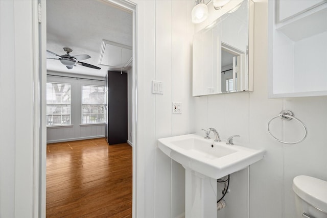 half bathroom with a ceiling fan, toilet, and wood finished floors