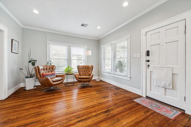 foyer with hardwood / wood-style flooring, baseboards, visible vents, and crown molding