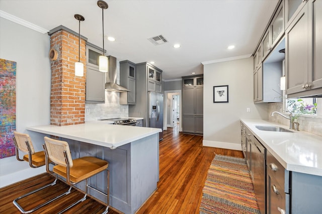 kitchen featuring visible vents, wall chimney exhaust hood, gray cabinets, stainless steel appliances, and a sink