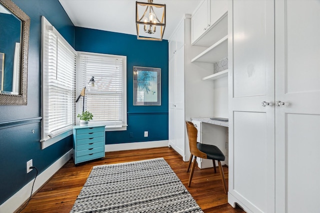 office space featuring dark wood-style floors, a notable chandelier, and baseboards