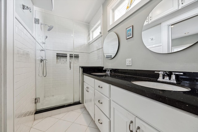 bathroom featuring a stall shower, double vanity, a sink, and tile patterned floors