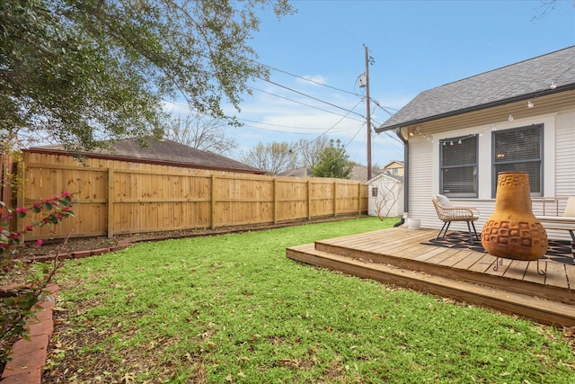 view of yard featuring an outbuilding, a fenced backyard, a deck, and a storage shed