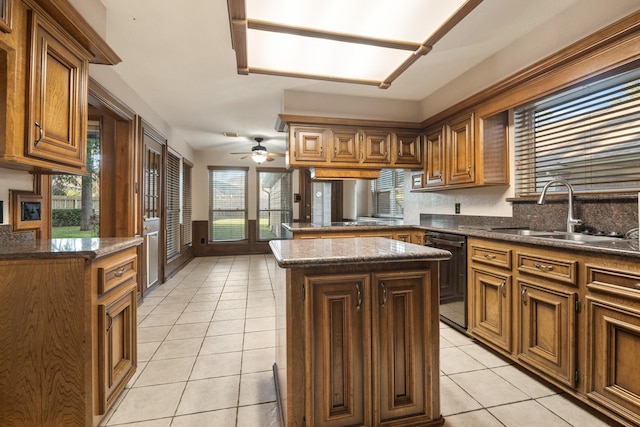 kitchen with a center island, black dishwasher, light tile patterned floors, brown cabinetry, and a sink