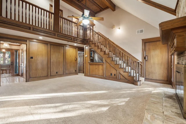 unfurnished living room featuring visible vents, a glass covered fireplace, stairway, vaulted ceiling with beams, and carpet