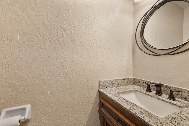 bathroom featuring a textured wall and vanity