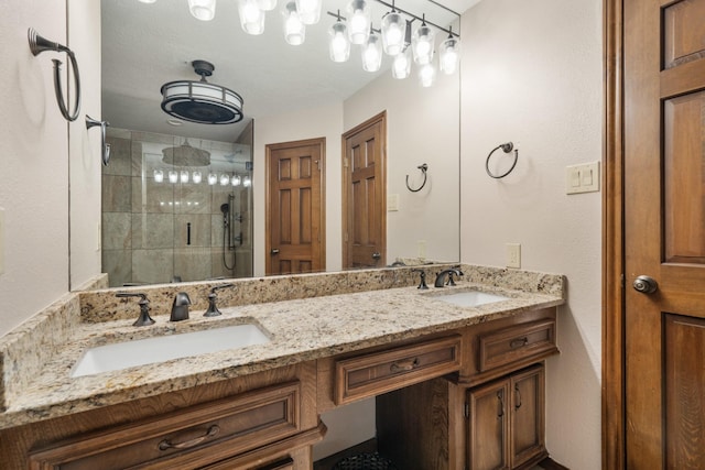 bathroom featuring double vanity, a stall shower, and a sink