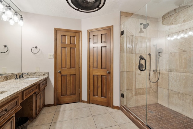 full bath featuring a stall shower, vanity, a textured ceiling, and tile patterned floors